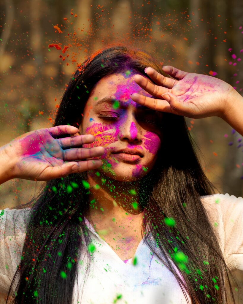 Vibrant portrait of a young woman enjoying Holi with colorful powders in Nepal.